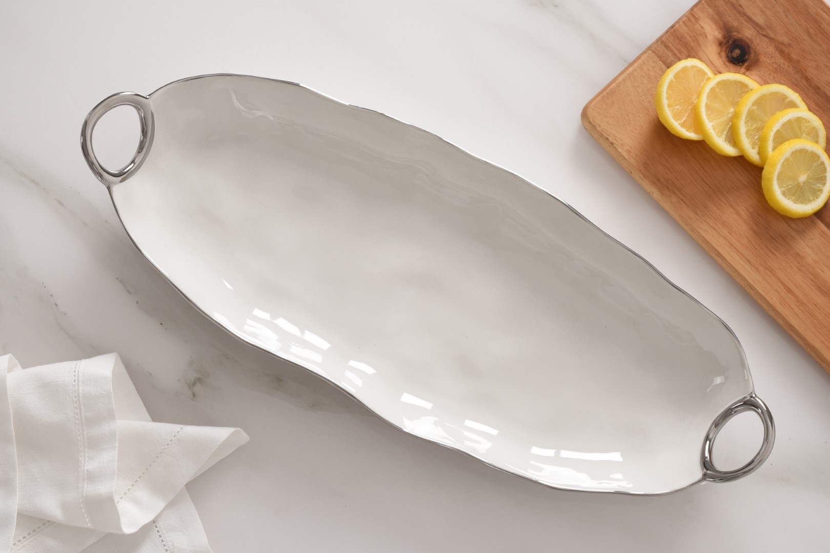 CER2673-5 cer2673 5 <p data-start="282" data-end="481">Порцелянове сервірувальне блюдо з витонченими ручками стане елегантним доповненням будь-якого столу. Біла порцеляна зі срібним титановим оздобленням підкреслює вишуканість сервірування, а великий розмір ідеально підходить для подачі основних страв, закусок, овочів або десертів.</p>